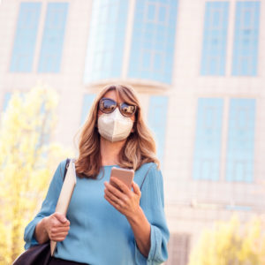 woman holding phone with face mask