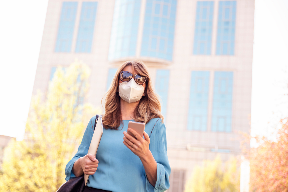 woman holding phone with face mask
